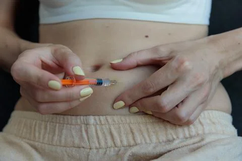 A Close-Up View of a Person Preparing to Inject Medication into Their Abdomen Stock Photos