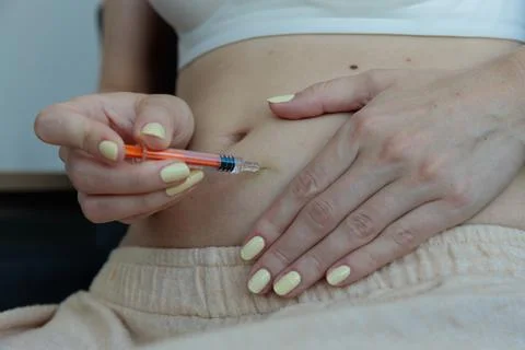 A Close-Up View of a Person Preparing to Inject Medication into Their Abdomen Stock Photos