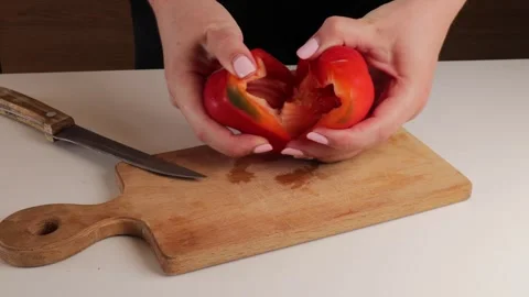 Close-up view of a person splitting a red bell pepper in half after slicing.. Stockbeeldmateriaal 320953497