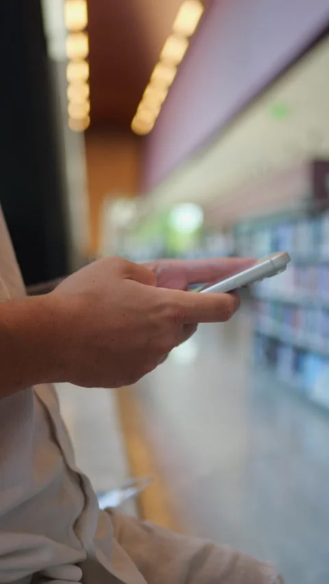 Close-Up View Of Person Using Smartphone Inside Library Environment... Vídeo Stock 334437388