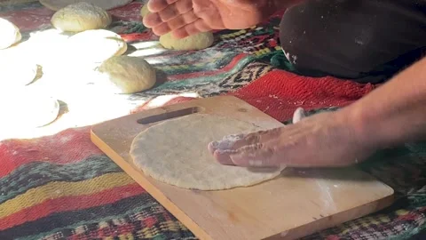 A close-up view of a person's hands flattening a ball of dough on a wooden Video stock 341898938