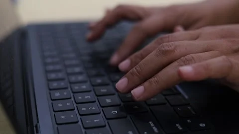 A close-up view of a person's hands typing rapidly on a dark computer or laptop Stock Footage 347992543