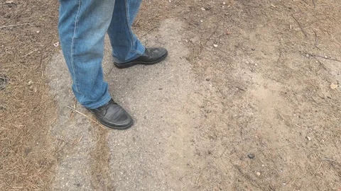 Close-up view of a person's shoes standing on a dirt and gravel surface surround Stock Footage 305565079