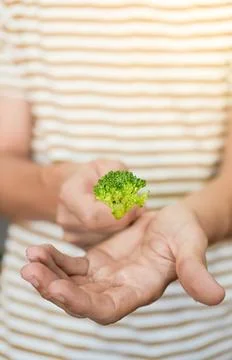 Close up view of piece of broccoli held by young man showing to camera. Healthy Stock Photos