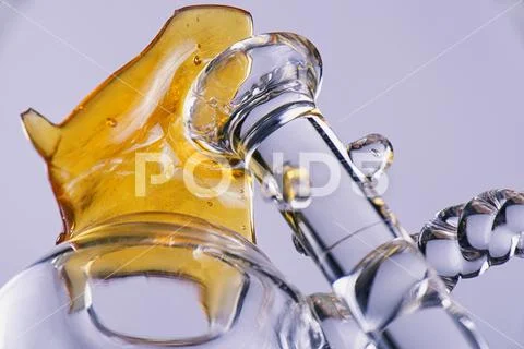 Close up view of a piece of cannabis oil concentrate aka shatter with glass.. Stock Photos