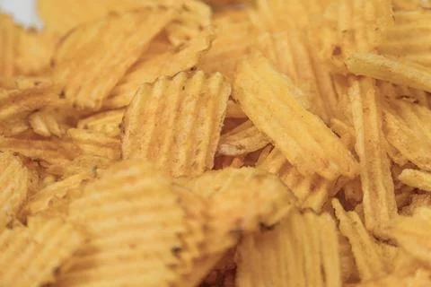 Close-up view of a pile of crispy yellow potato chips with ridges, under br.. Stock Photos