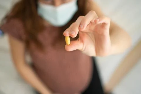 Close-up view of pill in hand. In the background is pregnant woman. Taking 스톡 사진