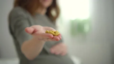 Close-up view of pills in hand. In background is pregnant woman. Taking vitamins Stock Footage 170516599