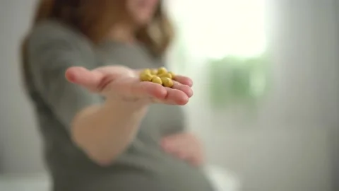 Close-up view of pills in hand. In background is pregnant woman. Taking vitamins Stock Footage 170819153