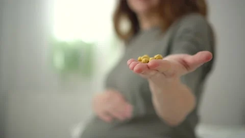 Close-up view of pills in hand. In background is pregnant woman. Taking vitamins Video stock 171755809