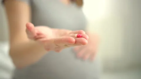 Close-up view of pills in hand. In background is pregnant woman. Taking vitamins Video stock 171833177