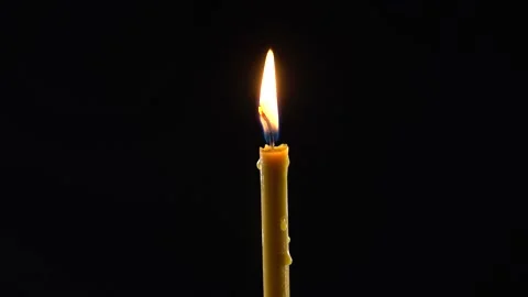 Close view plan. The flame of a yellow wax candle shines, black background. M Stock Footage 172193272