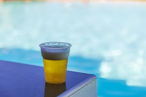 Close-up view of plastic cup filled with beer beside swimming pool. Greece. Stock-Fotos