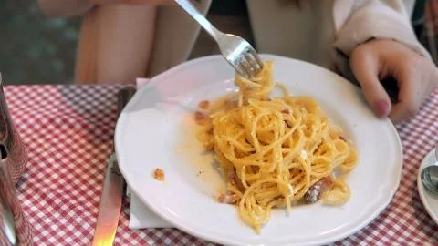 Close-up view of plate with spaghetti. Young happy woman sitting in cafe ang Stock Photos