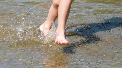 Close up view on playful kid legs running on wet sand in shallow water at the Stock Footage 160004306
