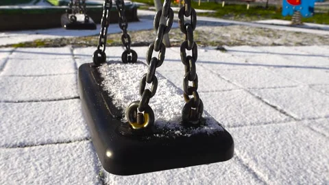 Close up view of a playground swing covered in first white snow during a sunny Stock Footage 321383442