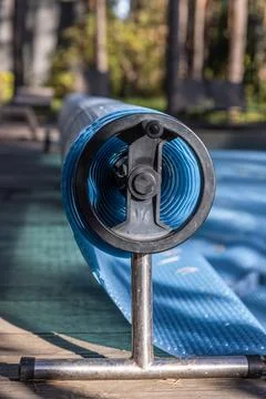 A Close-Up View of a Pool Cover Roller with a Blue Cover, Situated in a Sunlit Stock Photos