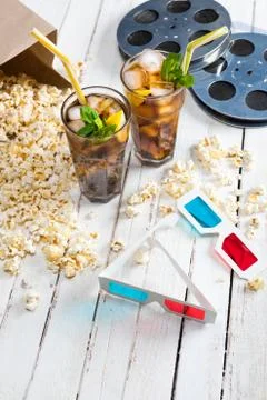 Close-up view of popcorn with iced tea, film reels and 3D glasses on table,.. Stock Photos