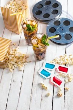 Close-up view of popcorn with iced tea, film reels and 3D glasses on table,.. Stock Photos