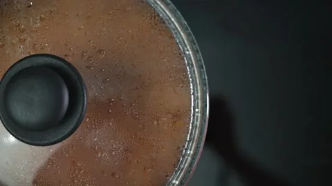 A close-up view of a pot on a stove, showcasing simmering contents with steam Vidéo 337112083