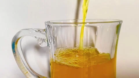 Close up view of pouring freshly squeezed orange juice into a clear glass m.. 動画素材 318126554