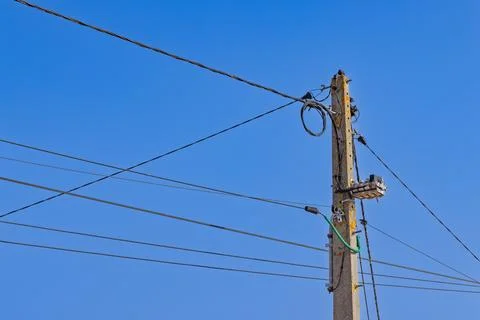 A close-up view of a power pole with multiple tangled wires and cables agains Stock Photos