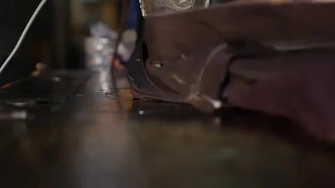 Close view of practiced fingers adjusting fabric on a sewing machine while Stock Footage 312213449