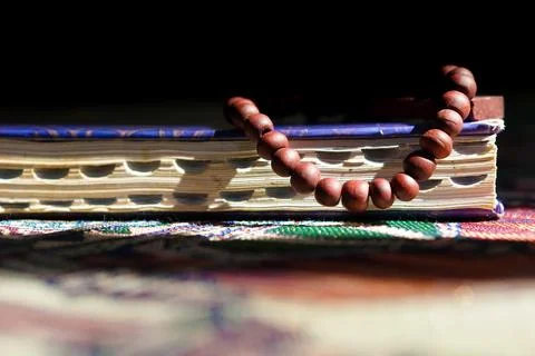 Close-up view of prayer beads on top of the Quran on a dark background Stock Photos