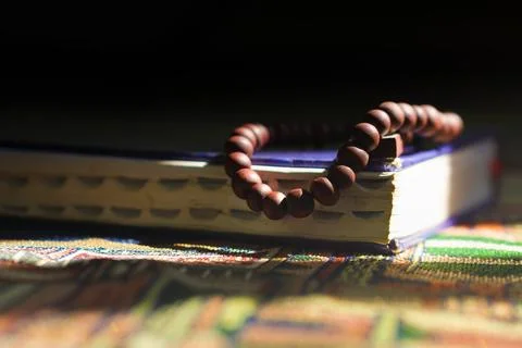 Close-up view of prayer beads on top of the Quran on a dark background Foto stock
