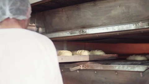 Close up view of the process of putting the dough bread into the oven. Baker Stock Footage 77513308