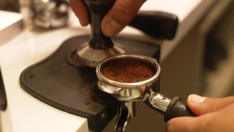 Close-up view of a professional barista pressing ground coffee into a Vídeos de archivo 339152653