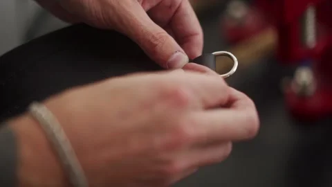 Close up view of professional leather craftsman attaches pin to handbag with Stock Footage 258798624