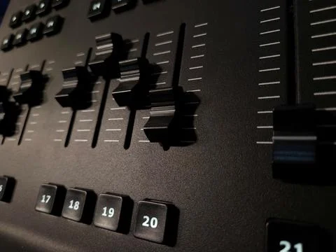 Close-up view of a professional lighting control panel with multiple sliders. Stock Photos