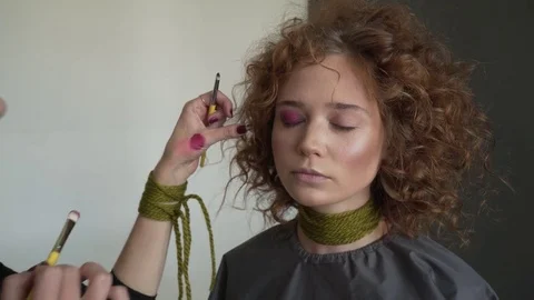 Close-up view to the professional makeup artist is applying red lip gloss to a Stock Footage 78999060