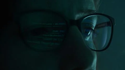 Close-up view of a programmer's eyes, with code projected on their glasses. 库存照片