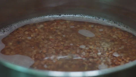 Close Up View of Raw Buckwheat Grains Boiling in a Metal Pot with Water Stock Footage 339646838