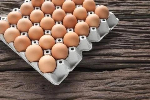 Close-up view of raw chicken eggs in egg box on old brown wooden background Stock Photos