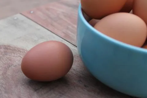 Close-up view of raw chicken eggs in blue bowl Foto stock