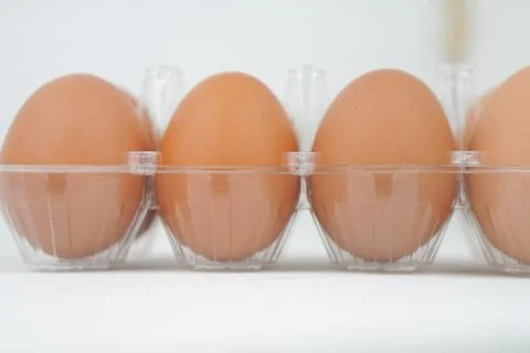 Close-up view of raw chicken eggs in egg box on white wooden background Stock Photos