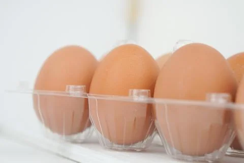 Close-up view of raw chicken eggs in egg box on white wooden background Stock Photos