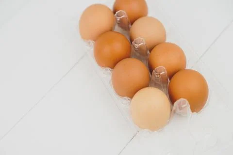 Close-up view of raw chicken eggs in egg box on white wooden background Stock Photos