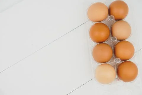 Close-up view of raw chicken eggs in egg box on white wooden background Stock Photos