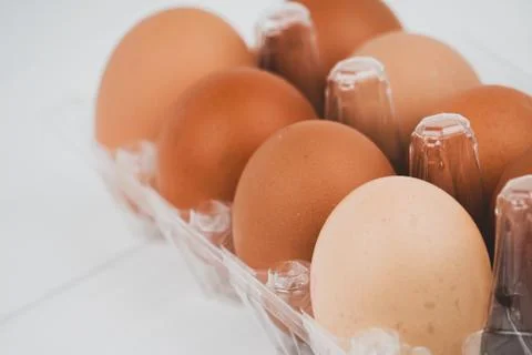 Close-up view of raw chicken eggs in egg box on white wooden background Stock Photos