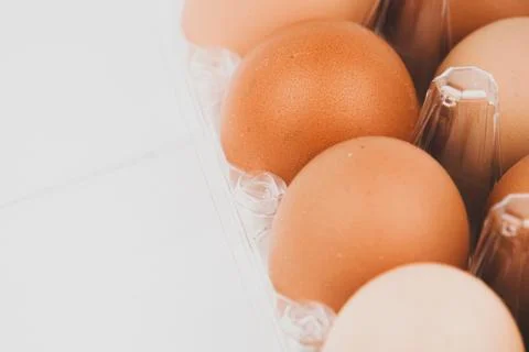 Close-up view of raw chicken eggs in egg box on white wooden background Stock Photos