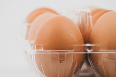 Close-up view of raw chicken eggs in egg box on white wooden background Fotos de archivo