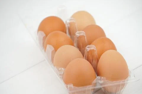 Close-up view of raw chicken eggs in egg box on white wooden background Stock Photos