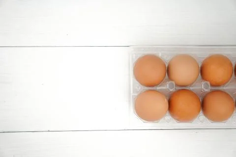 Close-up view of raw chicken eggs in egg box on white wooden background Stock Photos