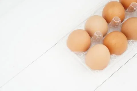 Close-up view of raw chicken eggs in egg box on white wooden background Stock Photos