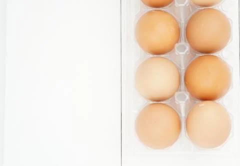 Close-up view of raw chicken eggs in egg box on white wooden background Stock Photos