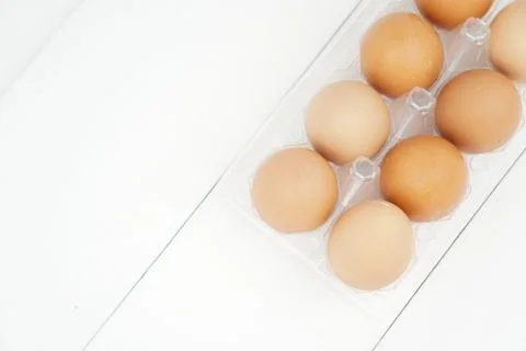 Close-up view of raw chicken eggs in egg box on white wooden background Stock Photos